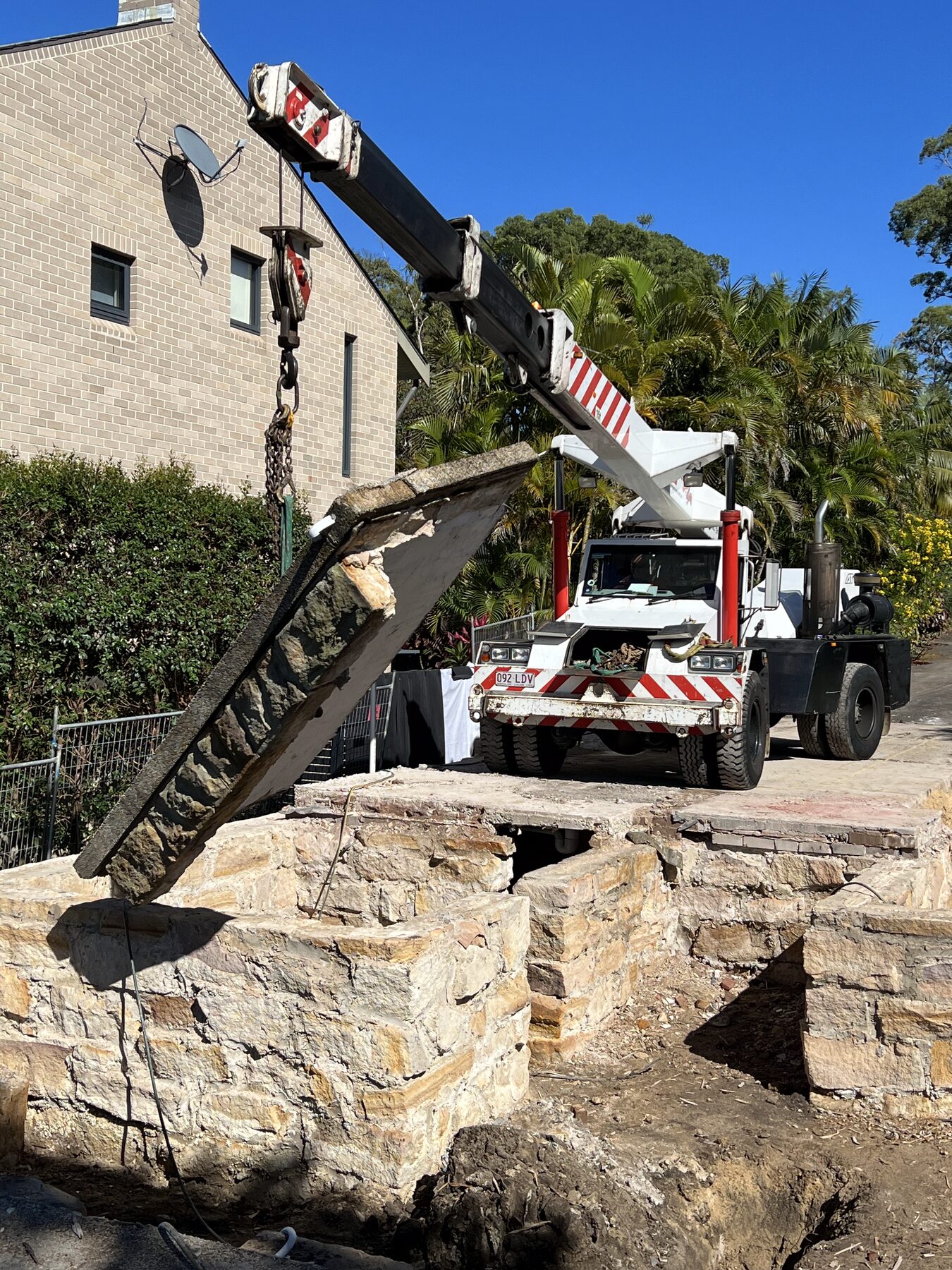 Franna crane lifting a sandstone block from a residential site at Woolooware